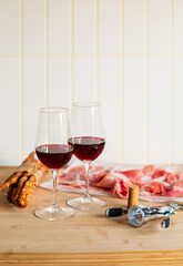 Two glasses of red wine with charcuterie, cheese, grapes and snacks