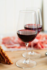 Two glasses of red wine with charcuterie, cheese, grapes and snacks