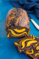 Pumpkin chocolate marble cake or bread on a blue concrete background. Dessert for Thanksgiving or Halloween.