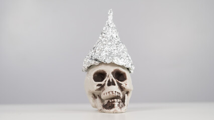 Plastic skull in a tinfoil cap on a white background. Copy space. 