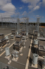 Electricity generating power plant showing high voltage insulators and a transmission tower.