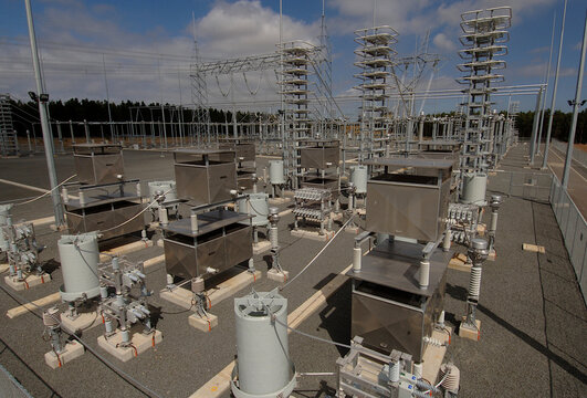 Electricity generating power plant showing high voltage insulators and a transmission tower.