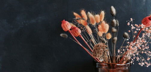 Dry flowers  and grass bouquet in a vase on black textured background with copy space banner....