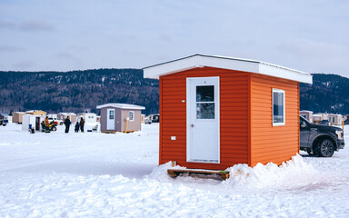 Orange ice fishing hut on the frozen Saguenay Fjord in la Baie, Quebec (Canada) on a winter day