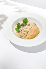 Traditional russian food - beef stroganoff with mushroom sauce and mashed potatoes. Beef stroganoff in white plate on light background with hard shadows. Stew meat with creamy sauce on summer menu.