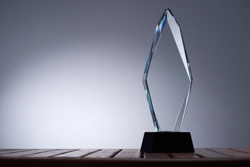 glass trophy on wood table against gray background