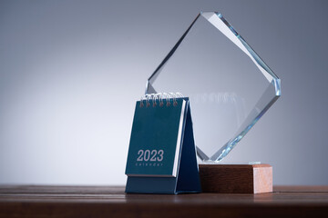 close up of a glass trophy and desk calendar 2023