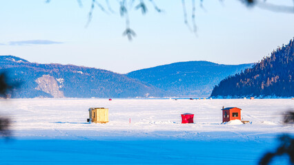 View on the colorful ice fishing hust installed on the frozen Saguenay fjord in winter in Quebec (Canada)