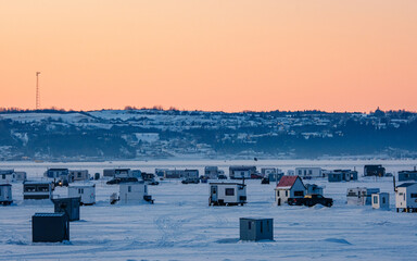 Colorful ice fishing huts on the frozen Saguenay fjord at sunset in La Baie, Quebec (Canada)