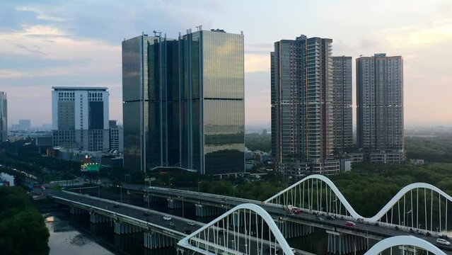 traffic driving on bridge in PIK area of Jakarta with modern high-rise buildings at dusk