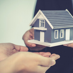 Sales manager or salesperson holds a demo house and has a home purchase contract with keys to...