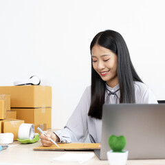 Asian businesswoman is taking online orders from a laptop and chatting with customers to confirm...