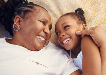 Happy, smile and family of a black grandma and child in happiness relaxing and lying on a bed at...