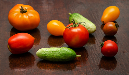 tomatoes and cucumbers scattered on a dark wooden background, vegetables