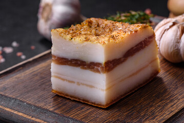 Smoked lard, bacon, half a piece, on a wooden dark cutting board