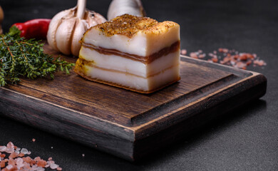 Smoked lard, bacon, half a piece, on a wooden dark cutting board