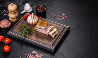 Smoked lard, bacon, half a piece, on a wooden dark cutting board