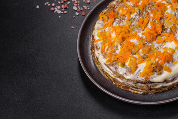 Delicious fresh liver cake with mayonnaise and carrots on a black plate against a dark concrete background