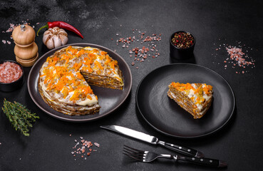 Delicious fresh liver cake with mayonnaise and carrots on a black plate against a dark concrete background