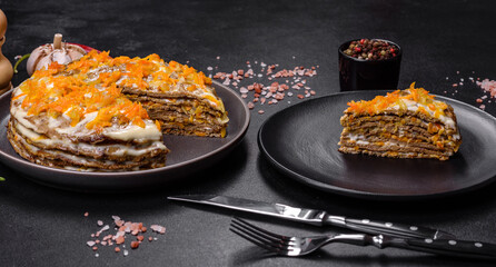 Delicious fresh liver cake with mayonnaise and carrots on a black plate against a dark concrete background