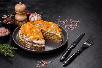 Delicious fresh liver cake with mayonnaise and carrots on a black plate against a dark concrete background