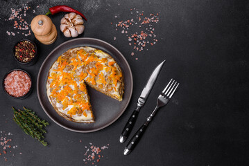Delicious fresh liver cake with mayonnaise and carrots on a black plate against a dark concrete background