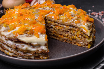 Delicious fresh liver cake with mayonnaise and carrots on a black plate against a dark concrete background