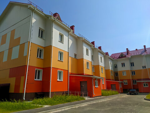 Noyabrsk, Russia - July 9, 2022: View of a bright three-story house with a parking area in a new microdistrict of the city