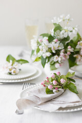 Fototapeta na wymiar Beautiful table decor for a wedding dinner with a spring blooming apple tree flowers. Celebration of a special event. Fancy white plates, wineglasses
