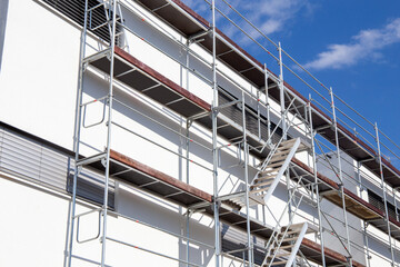 Gerüstbau, Malerarbeiten: Gerüst an einem neuen Apartmentgebäude mit weißem Fassadenanstrich