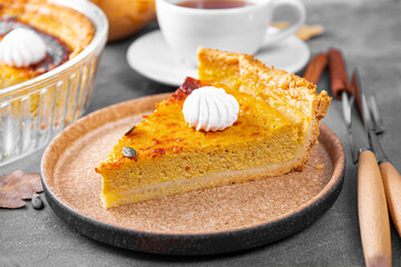  A piece of traditional American pumpkin pie with pecans and a cap of tea on the table, homemade pumpkin pie