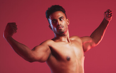 Bodybuilder, muscle and fitness with a nude man model posing shirtless in studio with a red...