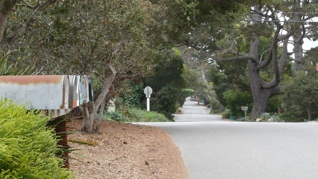 Typical generic suburban street, residential district with detached single-family houses, Carmel city road, Monterey, California USA. Trees grenery in neighborhood suburb. Dropbox, mailbox or postbox.