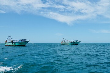 Fishing boats floating on the calm blue sea water in the Pamban island in Rameshwaram, Tamilnadu, India. Monsoon season fishing in India. Fishing boats in the harbor.