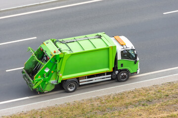 Recycling green truck rides on the road in the city.