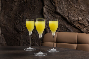 Three frozen cold cocktail glasses with limoncello on the wooden table of a restaurant