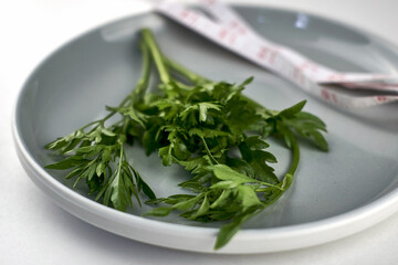 a plate of greens wrapped with a measuring tape, the concept of vegetarianism vegan diet