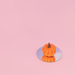 Autumn creative layout made with pumpkin on mirror on pastel pink background. Vintage retro...