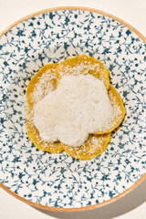 Italian ravioli with cheese and creamy sauce in ceramic plate on white table sunny day. Cheese ravioli with creamy espuma and parmesan. Italian ravioli with quattro formaggi filled and creamy overhead