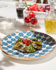 Grilled vegetables on light background with shadows. Salad with grilled zucchini, eggplant and tomatoes. Aesthetic composition with bbq vegetables. Vegan food. Grilled vegetables in Summer menu.