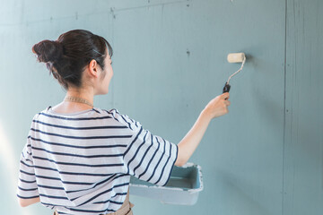 壁の塗装をする日本人女性（ペイントローラー）
