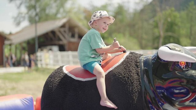 Kid on mechanical bull rodeo riding at western festival 4K