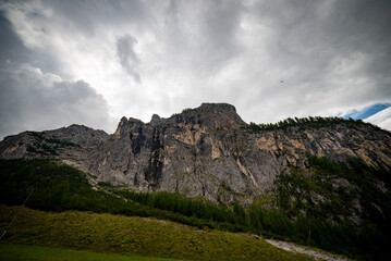 landscape with clouds over the mountains dolomiti monte Civetta, with blue sky and green trees in Italy