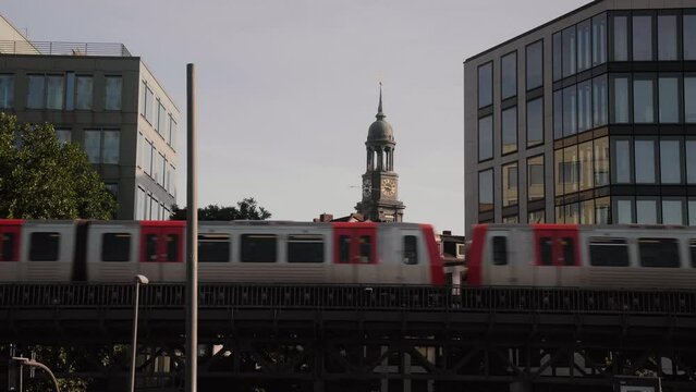 U-Bahn Subway train passing by at Baumwall with St. Michaelis Michel Church in the background.
