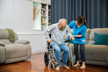 Asian nurse assisting helping senior man patient get up from wheelchair for practice walking at home, Smiling doctor support old man to getting up, help handicapped elderly stand up, healthcare - obrazy, fototapety, plakaty