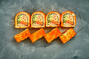 Sushi roll with salmon, crab and cucumber on gray background. Selective focus, noise added in post-production