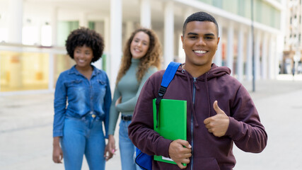 Young latin american male student with backpack and group of international students