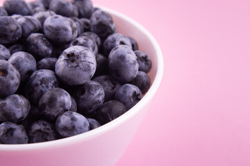 Blueberries on a macro scale. Dark berries in close-up. Ripe blueberries isolated on pink. Healthy, natural fruit..