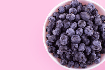 Fresh blueberries in white plate on pink background. Vegan and vegetarian concept. Summer healthy food. Flatlay