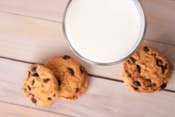 Glass of milk and brown cookies with chocolate. Oat, healthy cookies and milk cup, breakfast concept on kitchen. Copy space, flatlay.